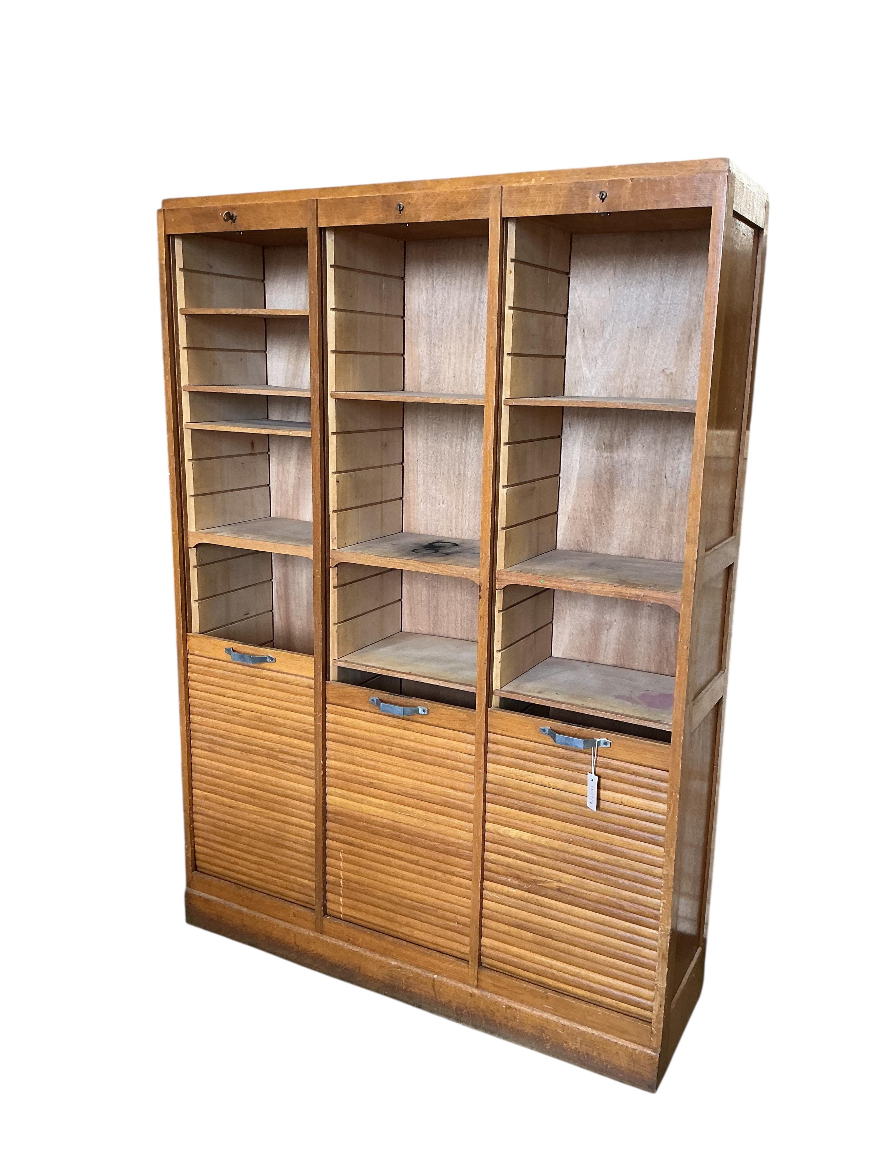 A mid 20th century oak triple tambour filing cabinet, width 126cm, depth 38cm, height 180cm